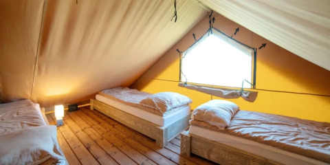Indretning af en safari telt-lodge med tre enkeltsenge i Weekend Glamping Resort, Italien.