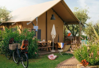 Safari Lodge telt ved Weekend Glamping Resort i Italien, omgivet af grønne planter, cykler og haveudstyr.
