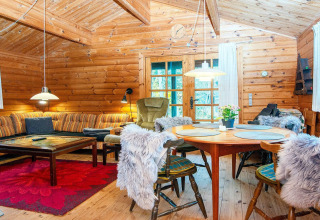 Knusse woonkamer in een Deens boshuis met houten interieur, zithoek, eettafel en gezellige sfeer.