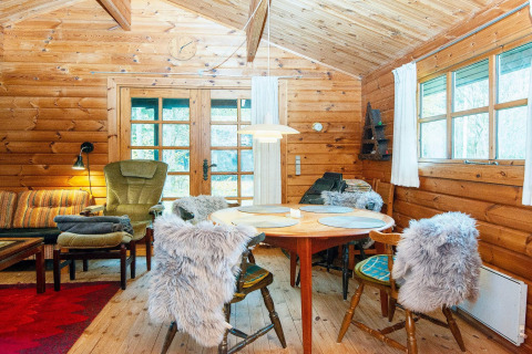 Gezellige houten eetruimte in een Deense cottage, met stoelen met bont en grote ramen met uitzicht.
