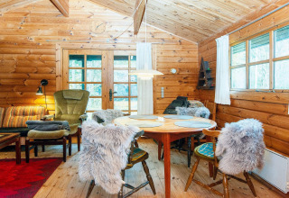 Gezellige houten eetruimte in een Deense cottage, met stoelen met bont en grote ramen met uitzicht.