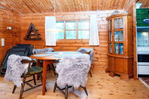 Knusse eetruimte in een prachtig houten huisje met ronde tafel, stoelen met pels en vitrinekast.