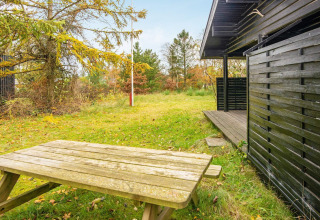 Buitenruimte van ‘Beautiful cottage near the river’ in Denemarken met picknicktafel, gras en terras.