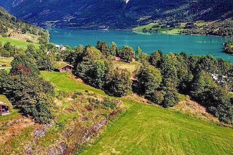 Uitzicht op een groene vallei met meer, bergen en houten chalets nabij Olden vanuit Deense chalet.