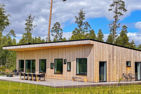 Moderna villa spaziosa sul lago con sauna, esterni in legno e grandi finestre immersa nella natura.