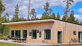 Moderna villa spaziosa sul lago con sauna, esterni in legno e grandi finestre immersa nella natura.