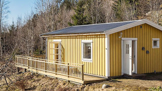 Gele houten chalet voor 4 personen met terras in Hällevadsholm, omgeven door bosrijke natuur.