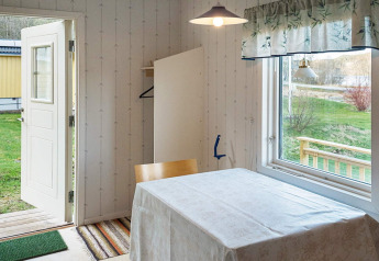 Open deur en tafel met tafelkleed in een vakantiehuis in Hällevadsholm, Zweden, uitzicht op tuin.
