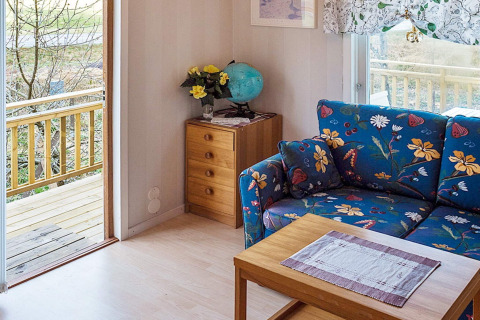Wohnbereich in einer Hütte in Hällevadsholm, Schweden, mit bunter Couch, Tisch und Blick auf die Veranda.