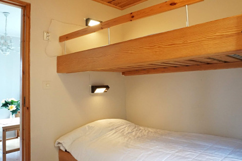 Chambre avec lit superposé en bois et literie blanche dans un chalet à Hällevadsholm, Suède.