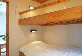 Chambre avec lit superposé en bois et literie blanche dans un chalet à Hällevadsholm, Suède.