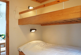 Zimmer mit Holz-Etagenbett und weißer Bettwäsche in einer Hütte in Hällevadsholm, Schweden.