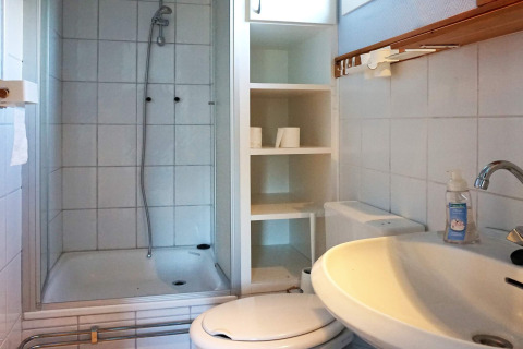 Compacte badkamer met douche, toilet, wasbak en schappen in een 4-persoonshuisje in Hällevadsholm, Zweden.