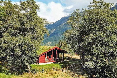 Rood vakantiehuis voor zes personen in Olden, Denemarken, tussen bomen en bergen gelegen.