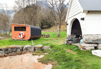 Buitenzicht bij een vakantiehuis in Olden, Denemarken, met sauna, gras en bergen op de achtergrond.
