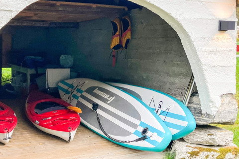 Espace de rangement dans un chalet à Olden avec deux kayaks rouges et deux paddles bleus, Danemark.