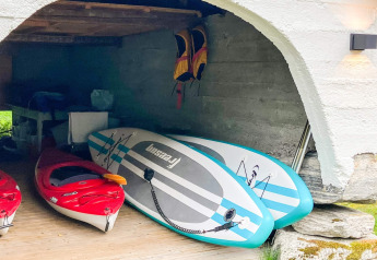 Opbevaringsområde i chalet i Olden med to røde kajakker og to blå oppustelige paddleboards, Danmark.