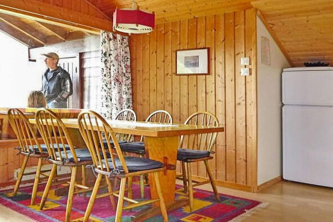 Eethoek in houten chalet, 6-persoons vakantiehuis in Olden, Denemarken, met tafel, stoelen en koelkast.