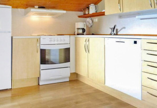 Moderne houten keuken met oven, vaatwasser en koffiezetapparaat in vakantiewoning in Olden, Denemarken.