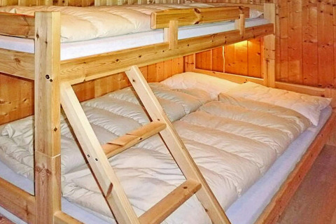 Letto a castello in legno con matrimoniale sotto e singolo sopra in uno chalet ad Olden, Danimarca.