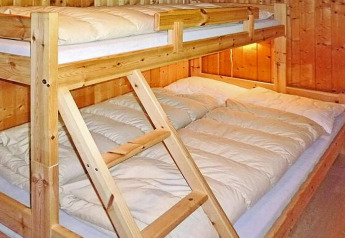 Houten stapelbed met een tweepersoonsbed onder en eenpersoonsbed boven in chalet Olden, Denemarken.