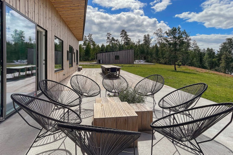 Patio esterno con sedie nere moderne presso la Spacious Lakeside Villa in Svezia, circondato dalla natura.
