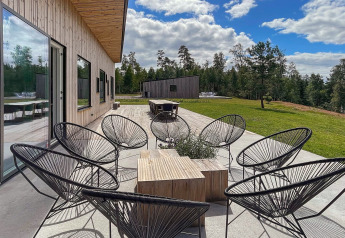 Patio esterno con sedie nere moderne presso la Spacious Lakeside Villa in Svezia, circondato dalla natura.