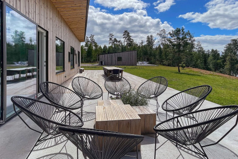 Terraza exterior con sillas y mesa modernas en la villa Spacious Lakeside Villa, rodeada de naturaleza en Suecia.