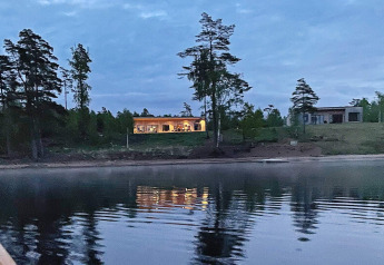 Photo du soir de la Spacious Lakeside Villa avec fenêtres éclairées au bord d’un lac en Suède.