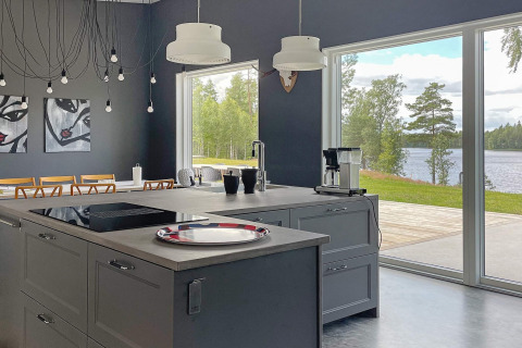 Moderne keuken in een ruime lodge met zicht op het meer in Zweden, grote ramen en kunst aan de muur.