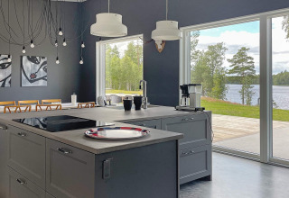 Cucina moderna in un’ampia villa sul lago in Svezia, con grandi finestre e vista panoramica.