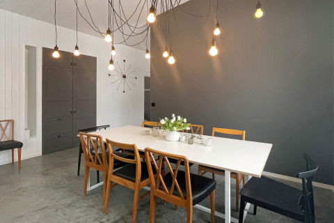Sala da pranzo di una spaziosa villa sul lago in Svezia, con luci moderne e sedie in legno accoglienti.
