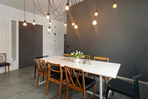 Eetruimte in een ruime villa aan het meer in Zweden, met moderne hanglampen en houten stoelen.