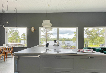 Moderne keuken met grote ramen en uitzicht over het meer en de natuur vanuit een villa in Zweden.