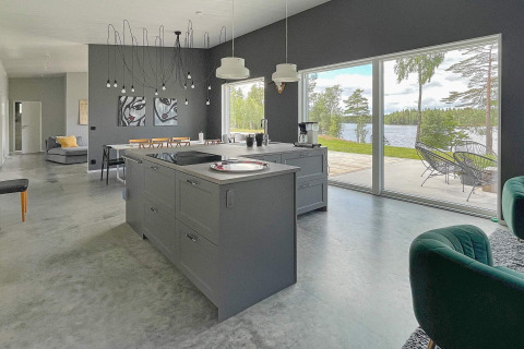 Moderne køkken og stue med store vinduer, der åbner ud til en søudsigt, lys og rummelig villa i Sverige.