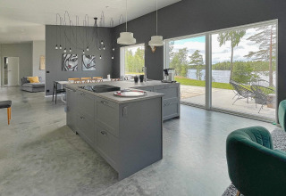 Modern kitchen and living area with large windows overlooking a lake, spacious lakeside villa in Sweden.
