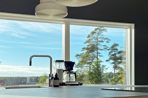 Moderne køkken med stor vindue og udsigt over sø og træer i en rummelig svensk villa.