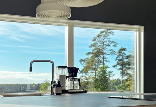 Cucina moderna con grande finestra e vista su lago e foresta in una spaziosa villa in Svezia.