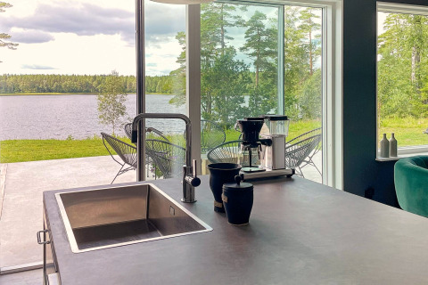 Isola cucina moderna con lavello, macchina caffè e vista lago nella villa sul lago in Svezia.