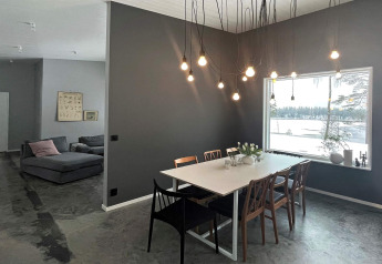 Moderne eetkamer in een Zweedse lodge met hanglampen, groot raam en uitzicht op een besneeuwd meer.