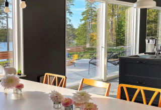 Sala da pranzo luminosa, ampie vetrate con vista su lago e bosco in una villa in Svezia.