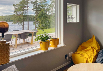 Interno di villa sul lago in Svezia, dettagli gialli e ampia finestra con vista panoramica sul lago.