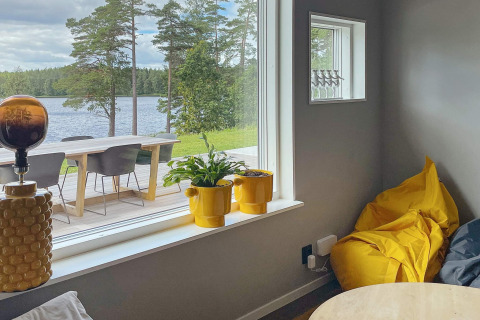 Interno di villa sul lago in Svezia, dettagli gialli e ampia finestra con vista panoramica sul lago.