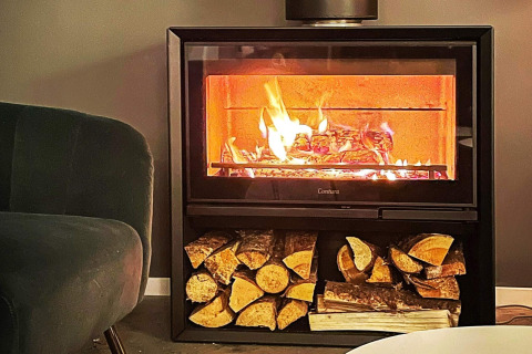 Caminetto accogliente con legna accatastata in una villa sul lago svedese, atmosfera rilassante.