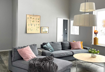 Moderne woonkamer van een ruime villa aan het meer in Zweden met grijze bank en grote ramen.