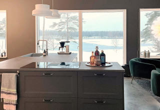 Cucina moderna in una villa spaziosa con grandi finestre e vista su un lago innevato in Svezia.