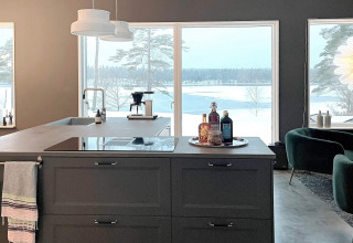 Moderne Küche in einer geräumigen Villa mit großen Fenstern und Blick auf eine verschneite Seelandschaft.