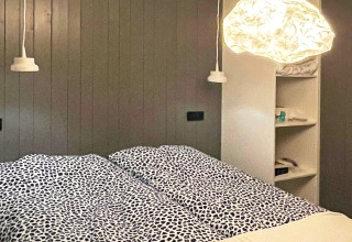 Camera moderna in una villa sul lago in Svezia con letti, lampade sospese e scaffalature a muro.