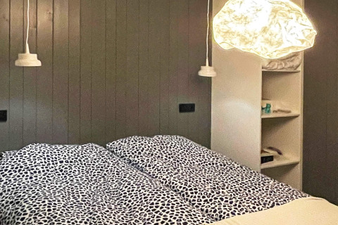Modernes Schlafzimmer in einer schwedischen Lodge mit Doppelbett, Hängelampen und Wandregalen.