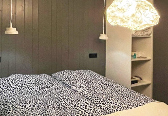 Modern slaapkamerinterieur in een Zweedse lodge met bedden, hanglampen en ingebouwde wandplanken.